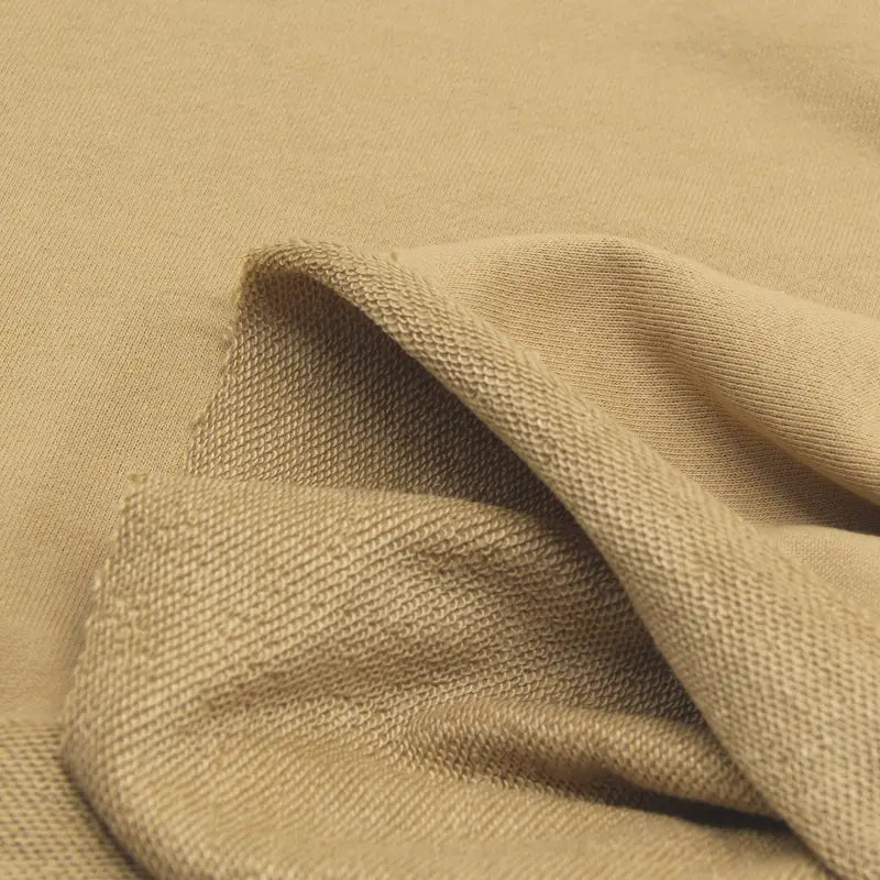A close-up of Longan Craft Solid Color Cotton French Terry Fabric by the yard, partially folded to reveal both its soft textured underside and smooth top surface—ideal thick material for hoodies.