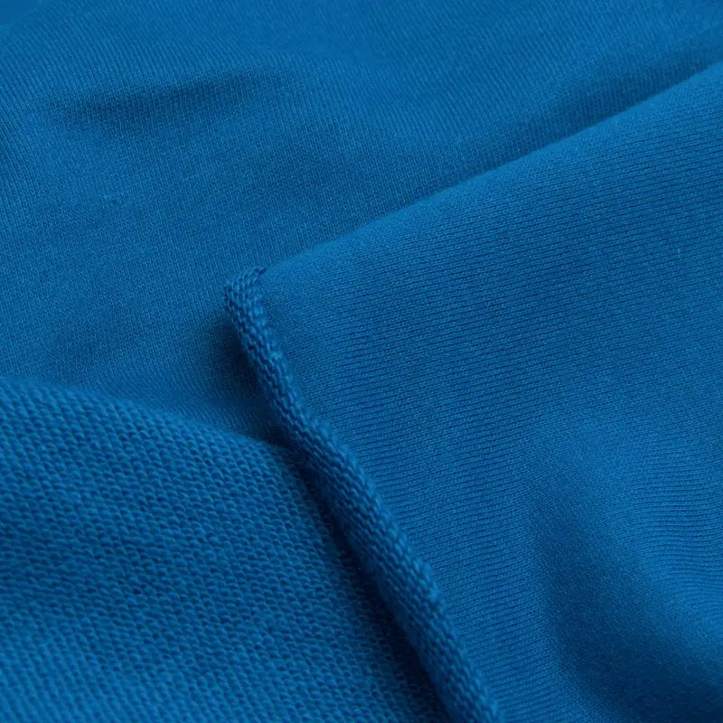 Close-up of Longan Craft Solid Color Cotton French Terry Fabric By The Yard shows two textures: one side smooth, the other more textured like sweatshirt fabric, separated by a seam. Ideal thick fabric for hoodies.