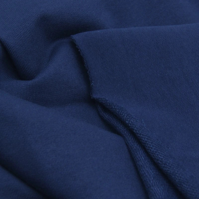 A close-up of Longan Craft's Solid Color Cotton French Terry Fabric by the yard, showcasing its dark blue thick material, soft texture, visible folds, and unfinished edge—perfect for hoodies.
