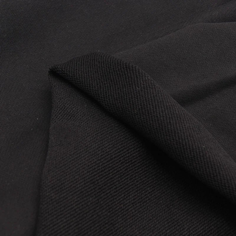 A close-up of Longan Craft’s Solid Color Cotton French Terry Fabric By The Yard shows both the textured and smooth sides, with a fold highlighting the contrast—ideal thick material for hoodies and other projects.