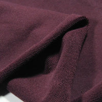 A close-up of Longan Craft Solid Color Cotton French Terry Fabric by the yard in maroon, highlighting its thick, soft texture and folded edge—perfect material for hoodies.