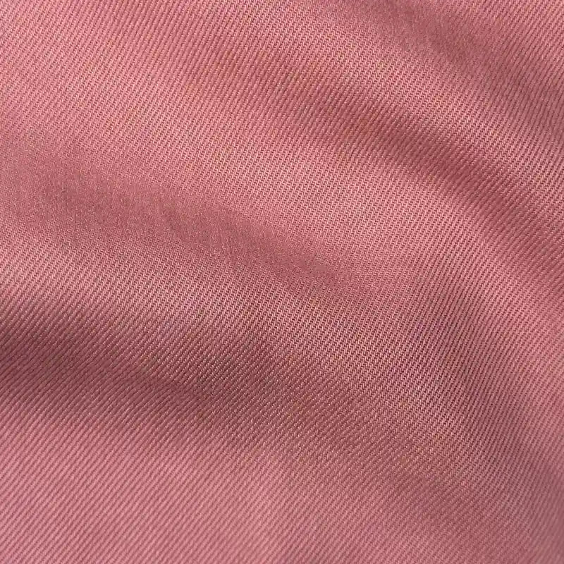 Close-up of Longan Craft's Solid Color Denim Lyocell Fabric By The Yard, showing textured pink, wrinkle-free material with diagonal lines and soft folds that highlight its breathable, comfy quality—ideal for jeans and apparel.