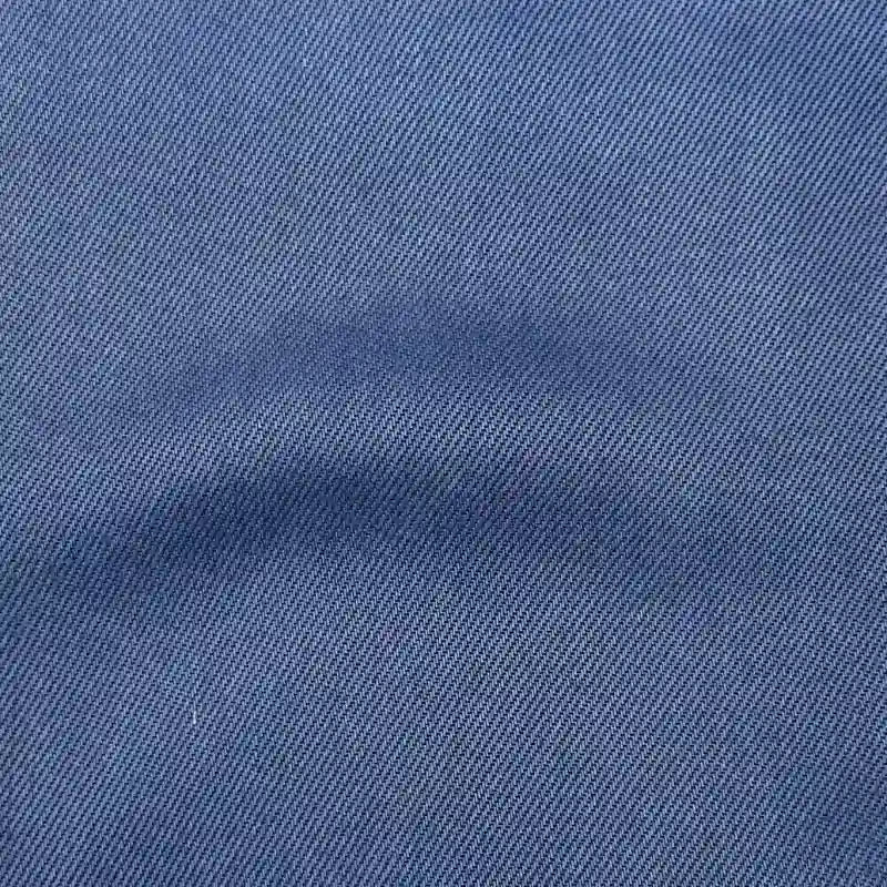 Close-up of Longan Craft's Solid Color Denim Lyocell Fabric By The Yard shows a diagonal twill weave and subtle center crease, highlighting this breathable, wrinkle-free material ideal for jeans.