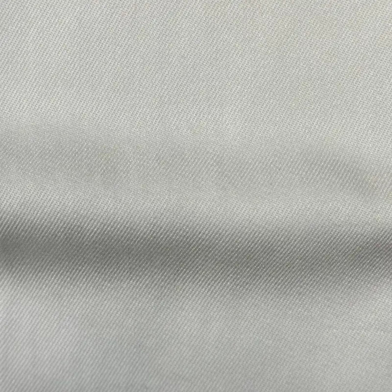 Close-up of Longan Craft’s Solid Color Denim Lyocell Fabric By The Yard shows its light gray, wrinkle-free material with a diagonal weave and visible fine threads—breathable, comfy, and perfect for sustainable jeans and fashion projects.