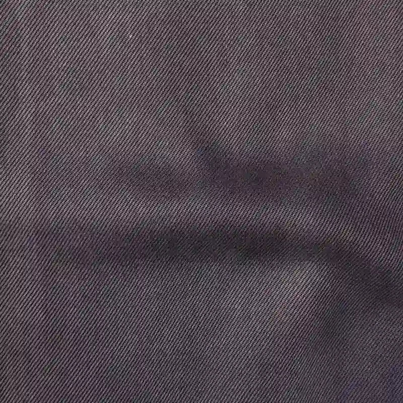 Close-up of Longan Craft’s Solid Color Denim Lyocell Fabric by the yard, showcasing its dark gray color, subtle diagonal ribbed texture, and faint crease. This breathable, wrinkle-free material is perfect for comfy jeans and more.