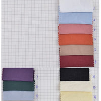 Nine rectangular swatches of Longan Craft’s Solid Color Double Sided Peachskin Fabric are arranged on grid paper, labeled 1–9 in blue. The microfiber polyester samples include shades like white, blue, red, brown, purple, black, green, and cream.