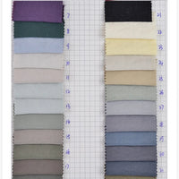 Two columns of hand-numbered Solid Color Double Sided Peachskin Fabric swatches by Longan Craft are shown on grid paper, displaying microfiber polyester hues from purple and green to beige, cream, and black.