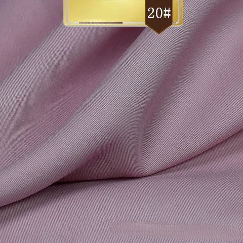 A close-up of Longan Craft’s Solid Color Linen Lyocell Fabric By The Yard with a fine, smooth texture. The sustainable, wrinkle-free twill Lyocell material is softly draped. A gold and brown label marked 20# appears in the top corner.