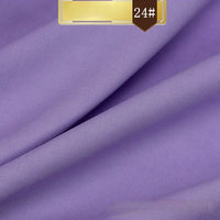 A close-up of smooth, folded purple Solid Color Linen Lyocell Fabric by Longan Craft, featuring a gold and brown 24# label. This wrinkle-free, sustainable textile blends elegance with eco-friendly lyocell for breathable dresses.