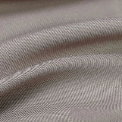 A close-up of Longan Craft's Solid Color Linen Lyocell Fabric By The Yard shows its fine textured, light gray, wrinkle-free twill lyocell material with soft shadows, perfect as a sustainable and breathable textile for dresses.