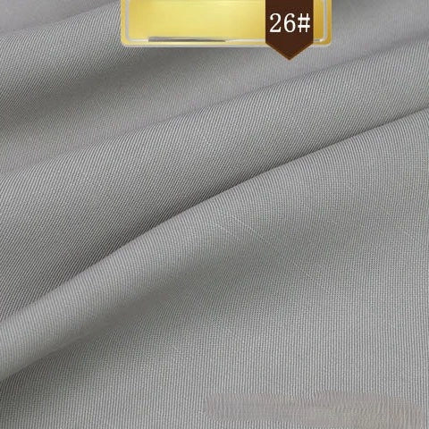 Solid gray Linen Lyocell Fabric by Longan Craft, featuring a subtle diagonal twill weave, folded for texture and drape. Gold and brown label in the corner reads 26#. Wrinkle-free, sustainable fabric ideal for dresses.