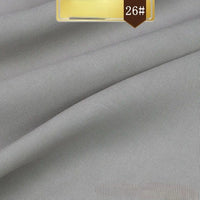 Solid gray Linen Lyocell Fabric by Longan Craft, featuring a subtle diagonal twill weave, folded for texture and drape. Gold and brown label in the corner reads 26#. Wrinkle-free, sustainable fabric ideal for dresses.