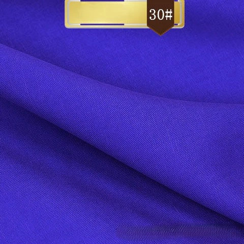 A close-up of Longan Craft’s Solid Color Linen Lyocell Fabric By The Yard shows its vibrant royal blue, smooth wrinkle-free twill texture, and neat folds. A brown "30#" label highlights this sustainable, breathable textile ideal for dresses.