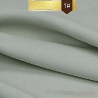 Solid Color Linen Lyocell Fabric by Longan Craft shown in light grey, folded in smooth, textured layers with a gold and brown "7#" label. Wrinkle-free, sustainable twill lyocell—ideal for dresses.