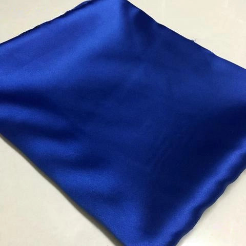 A yard of Longan Craft Solid Color Polyester Satin Fabric in royal blue, featuring a silky stretch satin texture, is neatly folded and displayed on a smooth, light-colored surface—ideal material for blouses.