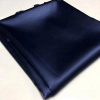 A neatly folded piece of Longan Craft's Solid Color Polyester Satin Fabric in dark navy blue, featuring a silky stretch satin texture, is placed on a light-colored surface—perfect material for blouses.