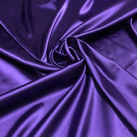 Longan Craft's Solid Color Polyester Satin Fabric by the Yard features a deep purple hue with a silky stretch texture, draping in glossy, swirling folds—ideal luxurious material for blouses and other elegant projects.