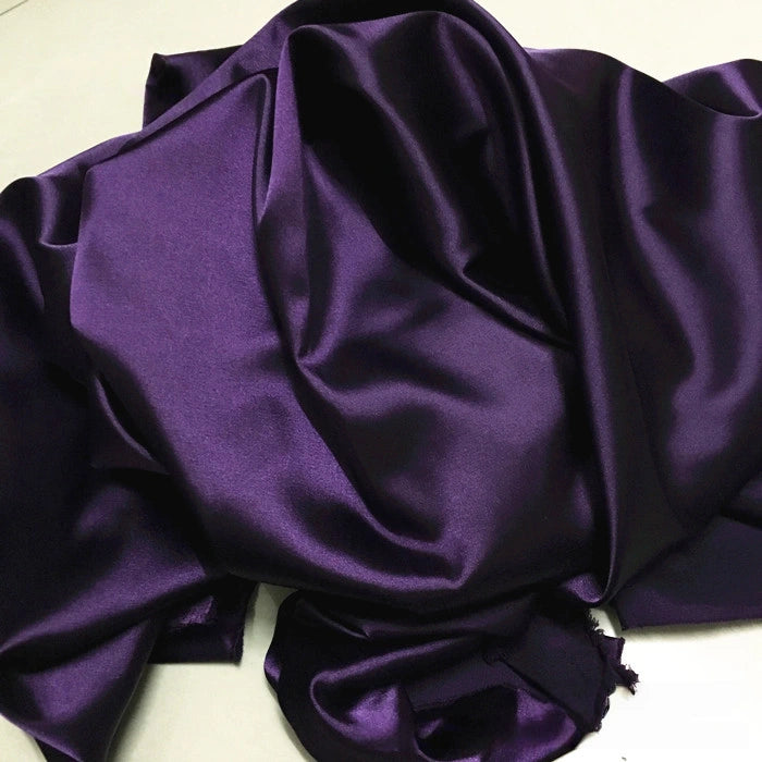 Longan Craft's Solid Color Polyester Satin Fabric By The Yard features a deep purple, silky stretch satin texture with a smooth, glossy finish—ideal for blouses and perfect for showcasing the elegant sheen of solid color satin.