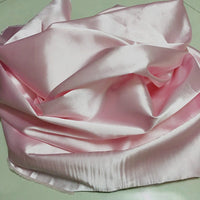 Longan Craft Solid Color Polyester Satin Fabric by the yard in light pink is loosely draped and gathered, highlighting its silky stretch texture and shiny, reflective surface—an ideal satin material for blouses.
