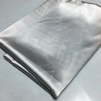 A folded piece of Longan Craft Solid Color Polyester Satin Fabric By The Yard rests on a light grey surface, showcasing its silky stretch satin texture and smooth, reflective finish—ideal material for blouses.