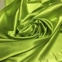 Longan Craft's Solid Color Polyester Satin Fabric by the yard features a lime green, silky stretch satin texture with glossy reflections—perfect material for blouses, beautifully arranged in gentle folds and swirls.