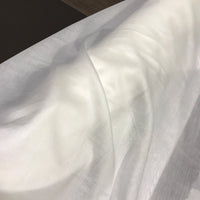 A length of Longan Craft’s Solid Color Ramie Fabric by the Yard, super lightweight and semi-sheer with a lyocell ramie blend, drapes smoothly over a surface, forming gentle folds and soft shadows. This breathable material adds an airy lightness and refined elegance—ideal for blouses and delicate projects.