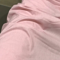 A close-up view of the Longan Craft Solid Color Ramie Fabric By The Yard in a soft, light pink shade, showcasing its gentle folds and creases. This super lightweight lyocell ramie material lies flat, highlighting its breathable texture—ideal for making blouses.
