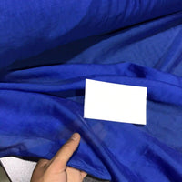 A hand holds the vibrant blue “Solid Color Ramie Fabric By The Yard” from Longan Craft, a super lightweight and breathable lyocell-ramie material for blouses, with a small blank white card placed on top to showcase its beauty.