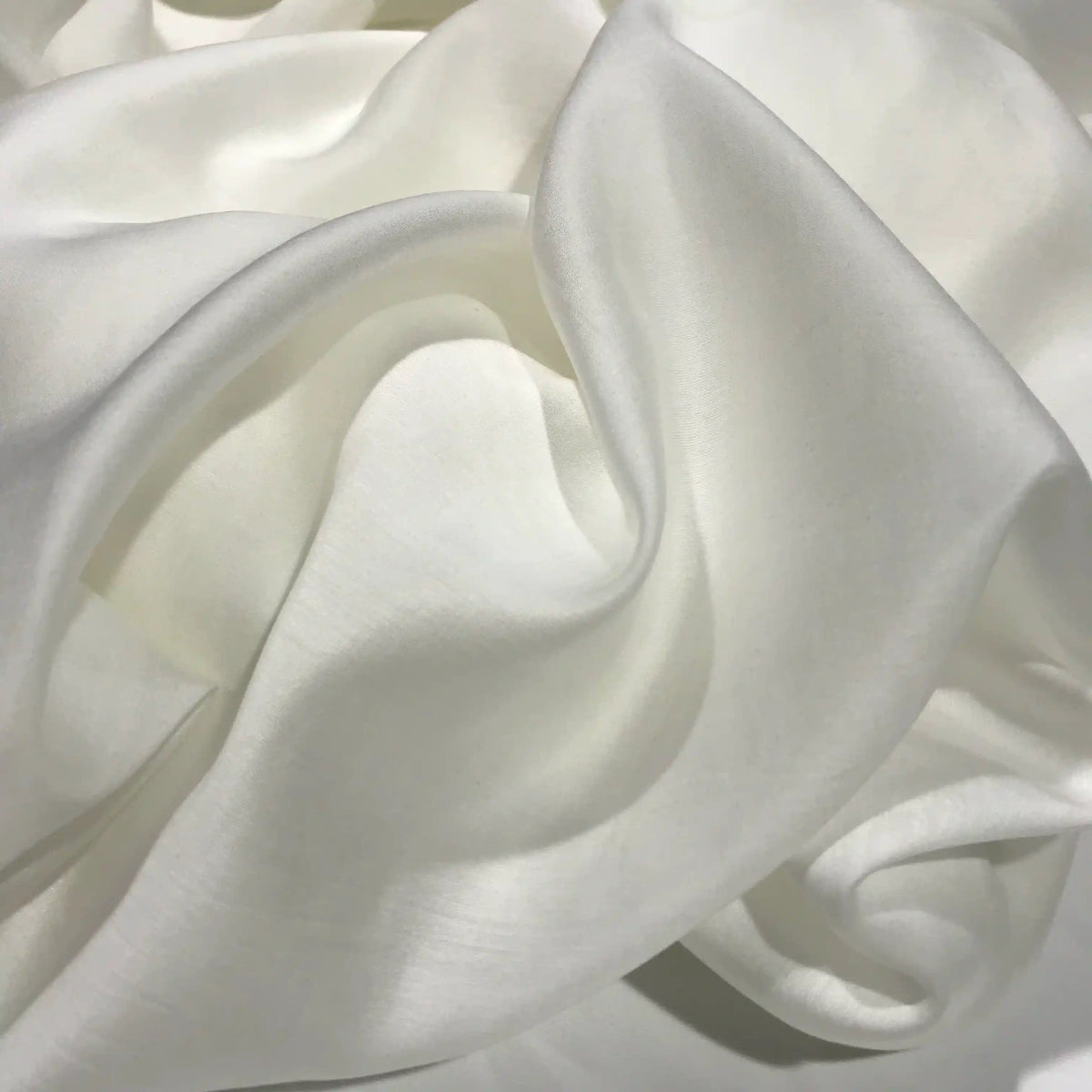 The Solid Color Ramie Fabric By The Yard from Longan Craft features a super lightweight lyocell ramie material in a soft, white hue. Draped in gentle folds, this breathable fabric creates smooth, flowing curves with a subtle sheen—perfect for blouses that offer both refined style and lasting comfort.