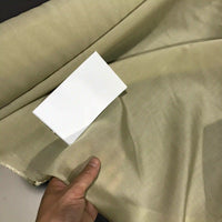 A hand displays a piece of Longan Craft’s Solid Color Ramie Fabric By The Yard, a super lightweight lyocell ramie material in light beige, with a white rectangular card placed on top for color comparison.