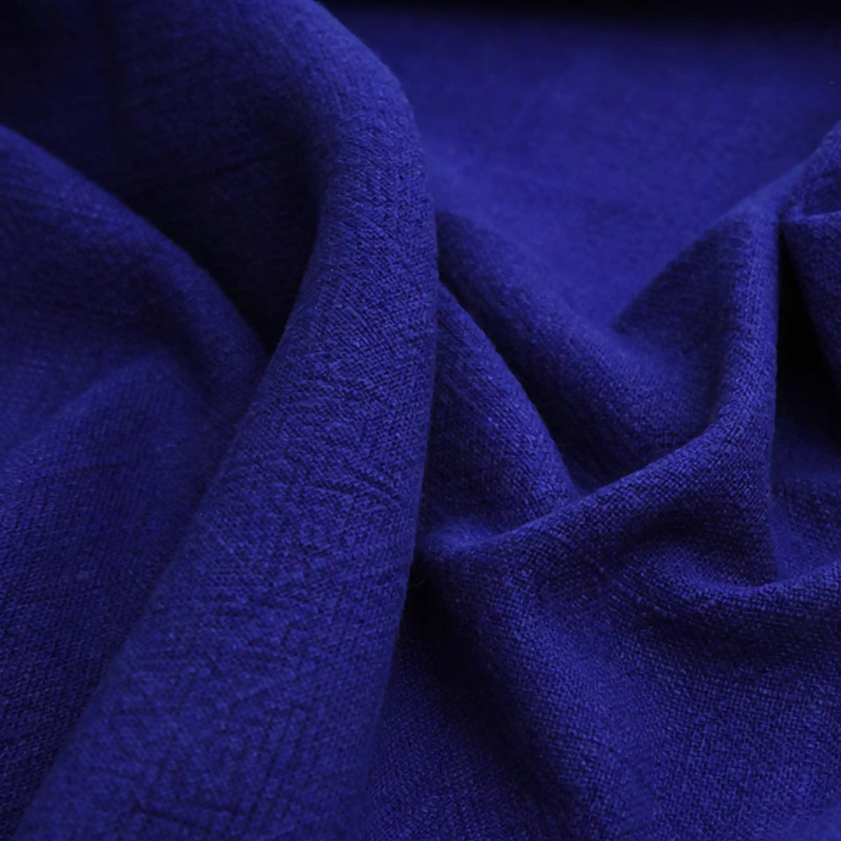 A close-up of Longan Craft’s Solid Color Rayon Linen Fabric by the Yard in deep blue, showing its thick washed slub weave, soft texture, gentle folds, and rich color—ideal viscose material for dresses and clothing projects.