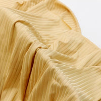 A close-up of Longan Craft’s Solid Color Ribbed Viscose Fabric by the yard, featuring light yellow soft folds, vertical ribbing, and gentle shadows—a stretchy, comfy elastane viscose material ideal for DIY T-shirts.