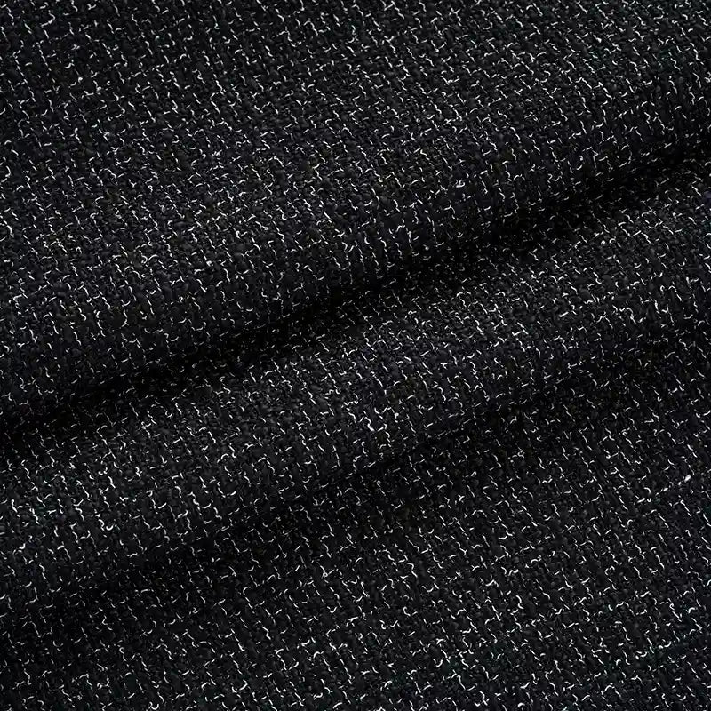 Close-up of Longan Craft Solid Color Tweed Fabric By The Yard—a woven polyester tweed for suits—showing fine white threads interlaced in black material, with subtle folds adding depth and shadows.