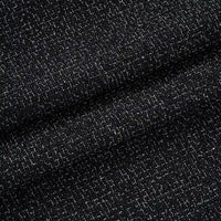 Close-up of Longan Craft Solid Color Tweed Fabric By The Yard—a woven polyester tweed for suits—showing fine white threads interlaced in black material, with subtle folds adding depth and shadows.