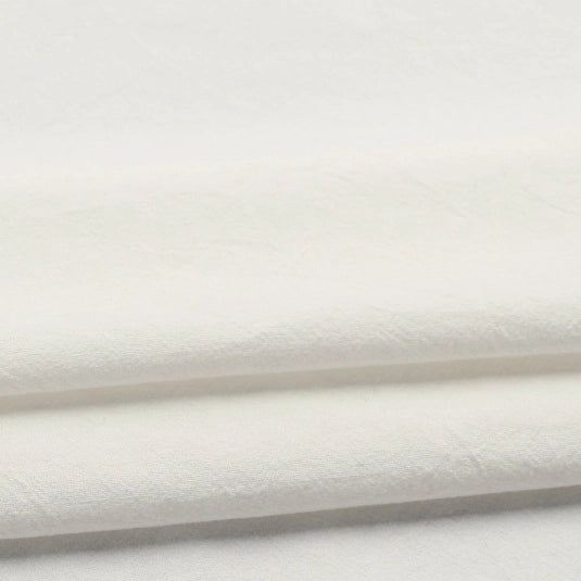 A close-up of two folded pieces of Longan Craft’s Solid Color Washed Crepe Fabric By The Yard, made from 100% cotton, highlights their soft textured surface and clean appearance—ideal for crafting pants and clothing.