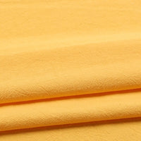 Three layers of the Longan Craft Solid Color Washed Crepe Fabric by the Yard, made from 100% cotton, are neatly folded. This pale yellow fabric features a soft, textured crepe surface with gentle creases throughout. Under the lighting, its smooth and slightly matte finish is accentuated.
