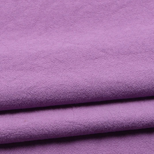 A close-up view of Longan Craft’s Solid Color Washed Crepe Fabric By The Yard, a 100% cotton crepe clothing material in light purple, featuring a soft, slightly textured surface ideal for pants.