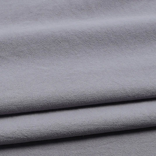 Close-up of Longan Craft Solid Color Washed Crepe Fabric By The Yard, featuring 100% cotton crepe material in light gray with a soft, textured surface, shown gently draping and folding—ideal for pants and clothing projects.