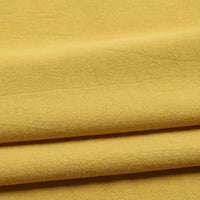 Close-up of folded Solid Color Washed Crepe Fabric By The Yard from Longan Craft in a mustard yellow hue, crafted from 100% cotton. The soft, lightly textured surface of this crepe clothing material creates gentle shadows as it folds, highlighting its smooth and lightweight quality—ideal for sewing pants and garments.