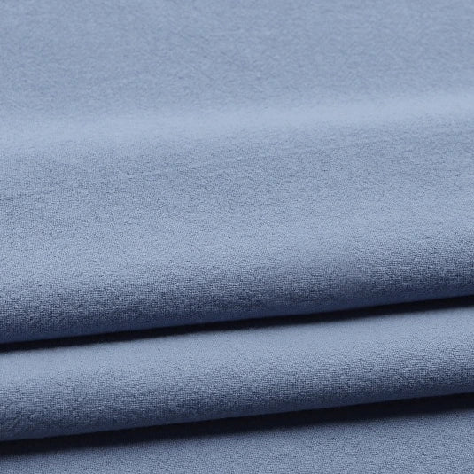 Longan Craft’s Solid Color Washed Crepe Fabric By The Yard features 100% cotton crepe material in a light blue shade, neatly folded to reveal subtle horizontal lines and shadows. With its soft, smooth texture and gentle drape, this evenly colored fabric is ideal for pants or any sewing project requiring a lightweight, solid color cotton crepe.