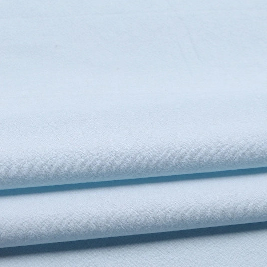Longan Craft’s Solid Color Washed Crepe Fabric by the Yard is shown here in light blue, folded neatly to highlight its 100% cotton composition and soft, textured crepe surface. The gentle shadows between the layers emphasize the fabric’s smooth drape—ideal for pants or other clothing projects.