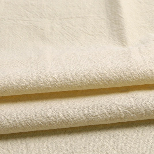 Close-up of Longan Craft’s Solid Color Washed Crepe Fabric by the Yard, made from 100% cotton with a soft, textured crepe finish in an off-white shade, displaying natural creases and folds for a relaxed, organic look—ideal for pants and clothing projects.