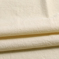 Close-up of Longan Craft’s Solid Color Washed Crepe Fabric by the Yard, made from 100% cotton with a soft, textured crepe finish in an off-white shade, displaying natural creases and folds for a relaxed, organic look—ideal for pants and clothing projects.