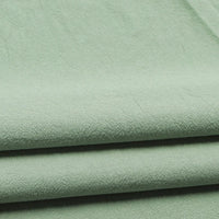 Close-up of three neatly folded layers of Longan Craft Solid Color Washed Crepe Fabric By The Yard, made from 100% cotton. This light green fabric features a soft, slightly textured surface and appears smooth and lightweight—ideal for pants, clothing, or home textiles.
