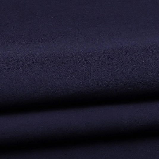 A close-up of Longan Craft Solid Color Washed Crepe Fabric by the yard, made from 100% cotton with a soft, textured surface in dark navy blue, featuring gentle folds and subtle shadows—ideal for pants and clothing projects.