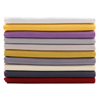 A neat horizontal stack of Longan Craft Solid Color Washed Crepe Fabric by the yard, made from 100% cotton, is displayed in an array of colors—white, yellow, purple, gray, beige, black, and red—against a white background. The soft textured crepe fabric is ideal for making pants and other clothing projects.