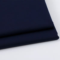 A close-up of neatly folded Solid Color Wool Gabardine Fabric By The Yard from Longan Craft, a rayon polyester blended twill gabardine textile, on a white surface, highlighting its smooth texture and clean edges—ideal for casual wear.