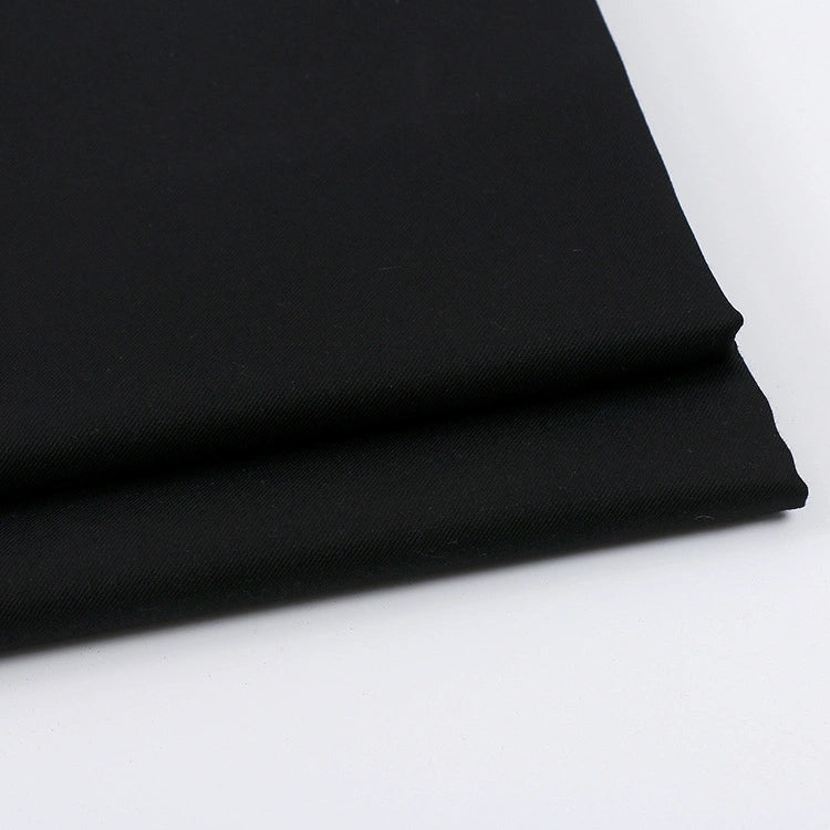 A close-up of Solid Color Wool Gabardine Fabric by Longan Craft, a black rayon polyester blended twill ideal for casual wear, shown folded on a white surface.