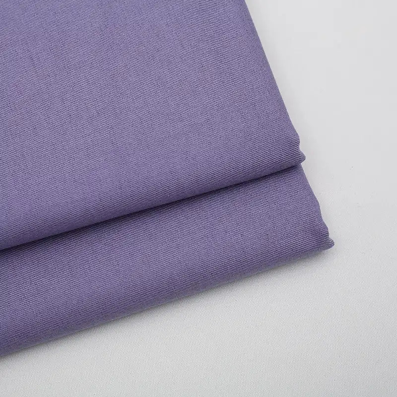 Two neatly folded pieces of Longan Craft Solid Color Wool Gabardine Fabric are stacked on a white surface, featuring a smooth and slightly textured rayon-polyester blended twill ideal for casual wear.