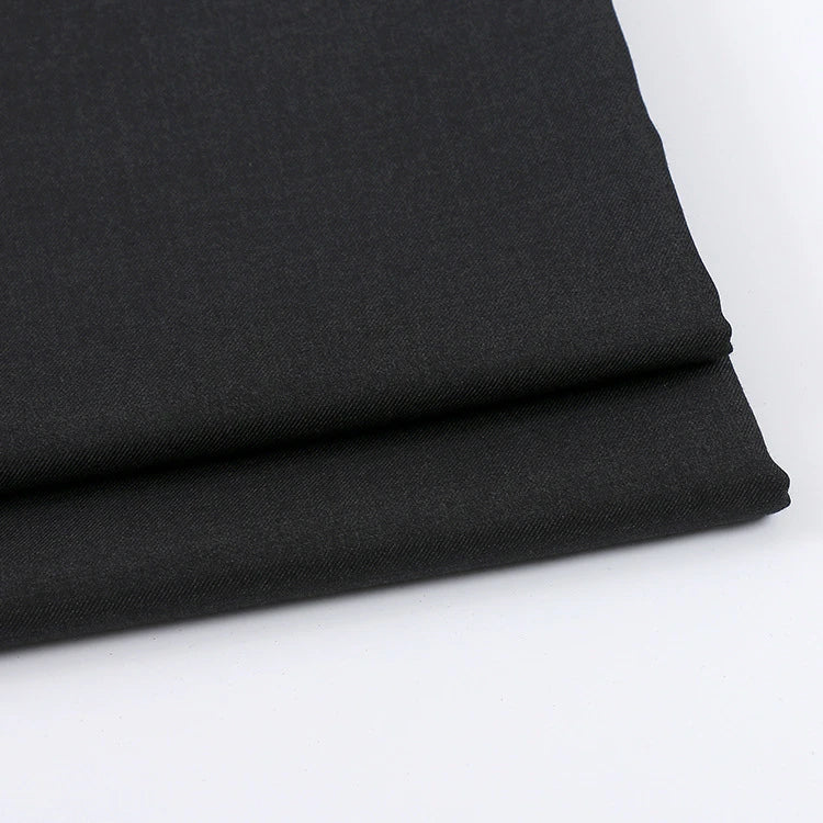 A close-up of two neatly folded pieces of Longan Craft Solid Color Wool Gabardine Fabric, a rayon polyester blended twill ideal for casual wear, displayed on a white surface.